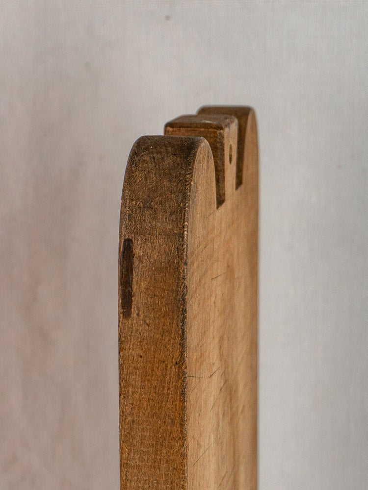 Antique French double-lobed hardwood cutting board with rounded, notched edges on a light background.