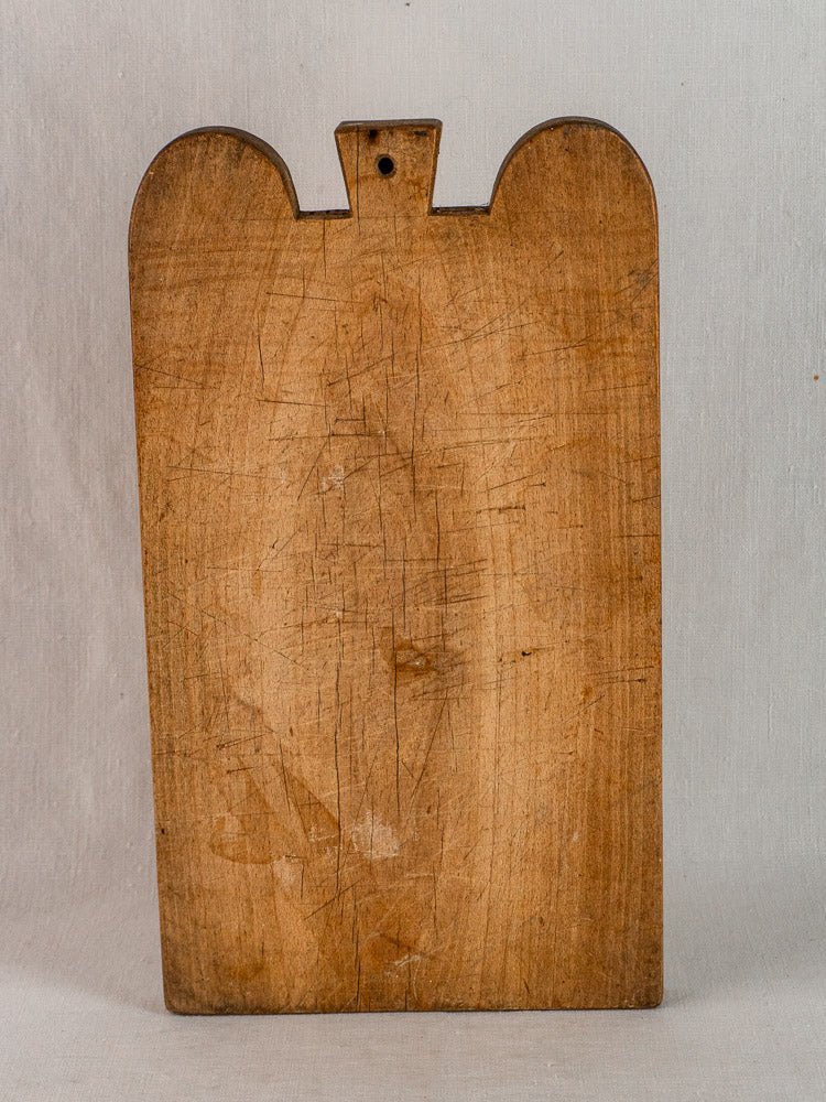 Antique French hardwood cutting board with double-lobed top and knife marks against a light gray background.
