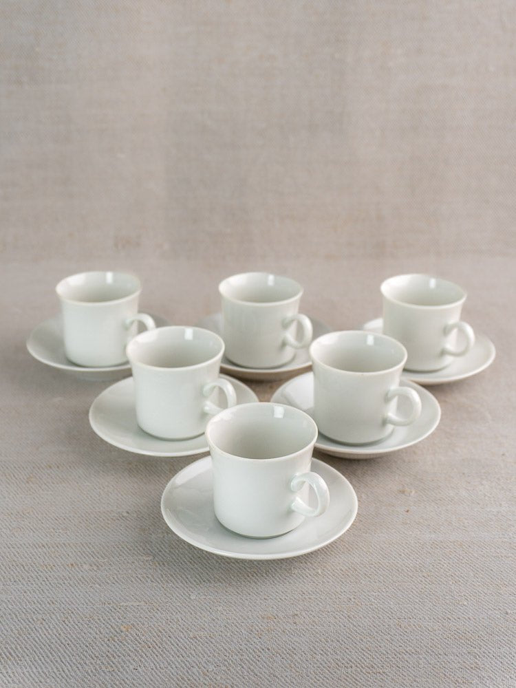 Set of six vintage Hutschenreuther porcelain espresso cups with saucers on a beige textured surface.