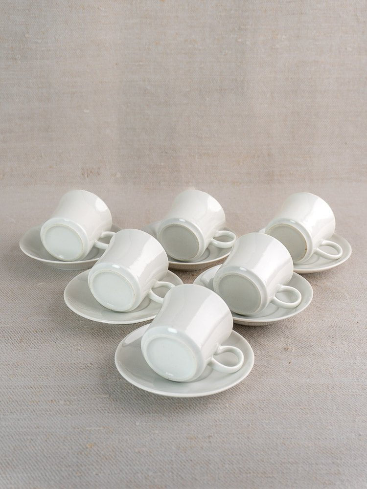 Set of six white porcelain Hutschenreuther espresso cups with saucers, elegantly arranged on neutral fabric.