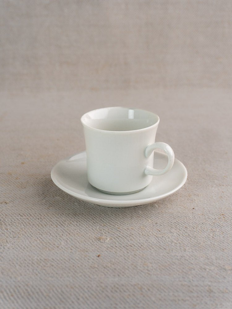 White ceramic teacup with handle on matching saucer, vintage Hutschenreuther German porcelain demitasse.
