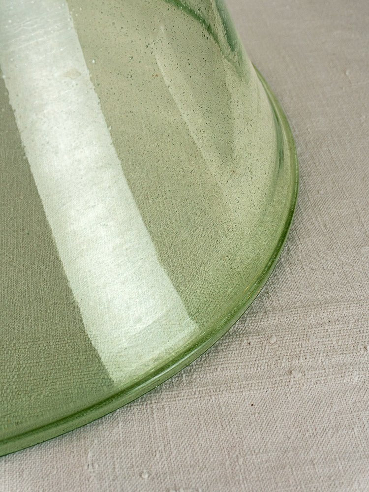 Antique French hand-blown glass garden cloche in pale green, 19th century, on textured beige fabric.