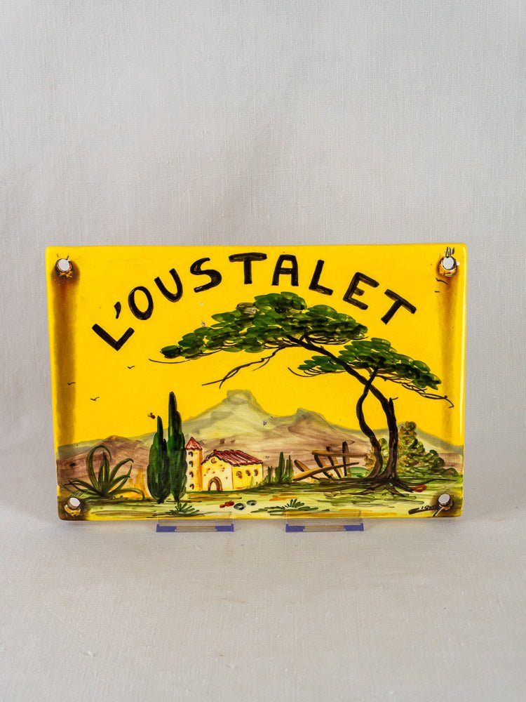 Hand-painted French faience house plaque with “LOUSTALET” and Provençal landscape on yellow ceramic.