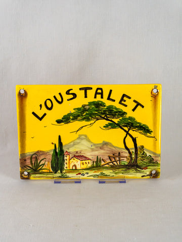 Hand-painted French faience house plaque with “LOUSTALET” and Provençal landscape on yellow ceramic.