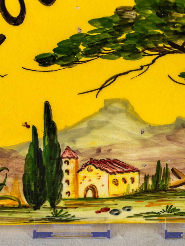 Hand-painted French faience plaque with Provençal landscape, yellow house, red roof, green trees, mountain backdrop.