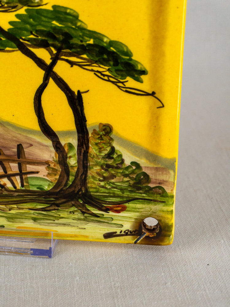 L’Oustalet French faience house plaque with hand-painted Provençal landscape on vibrant yellow, secured by visible screw.
