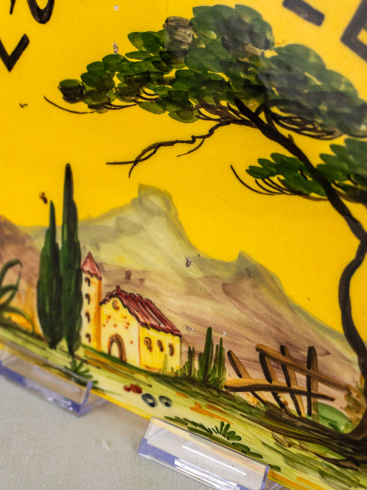 Hand-painted L’Oustalet French faience house plaque with Provençal landscape and yellow building, on bright yellow surface.