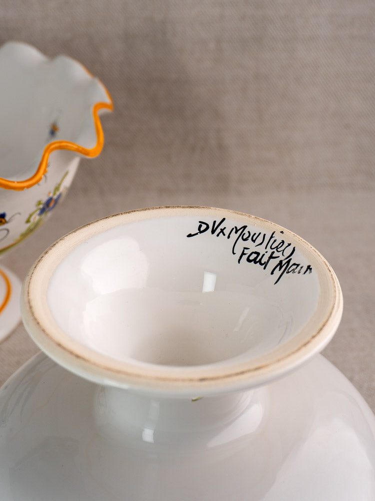 White ceramic vase base with handwritten signature; vintage French Moustiers-style faience compote visible behind.