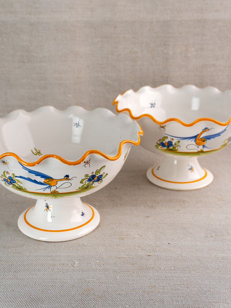 Pair of vintage French Moustiers-style faience compotes with scalloped edges, floral and insect motifs.
