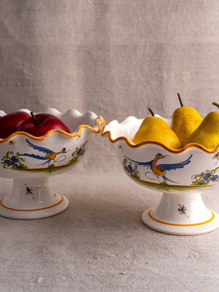 Pair of vintage French Moustiers-style compotes hand-painted with birds and flowers, holding apples and pears.