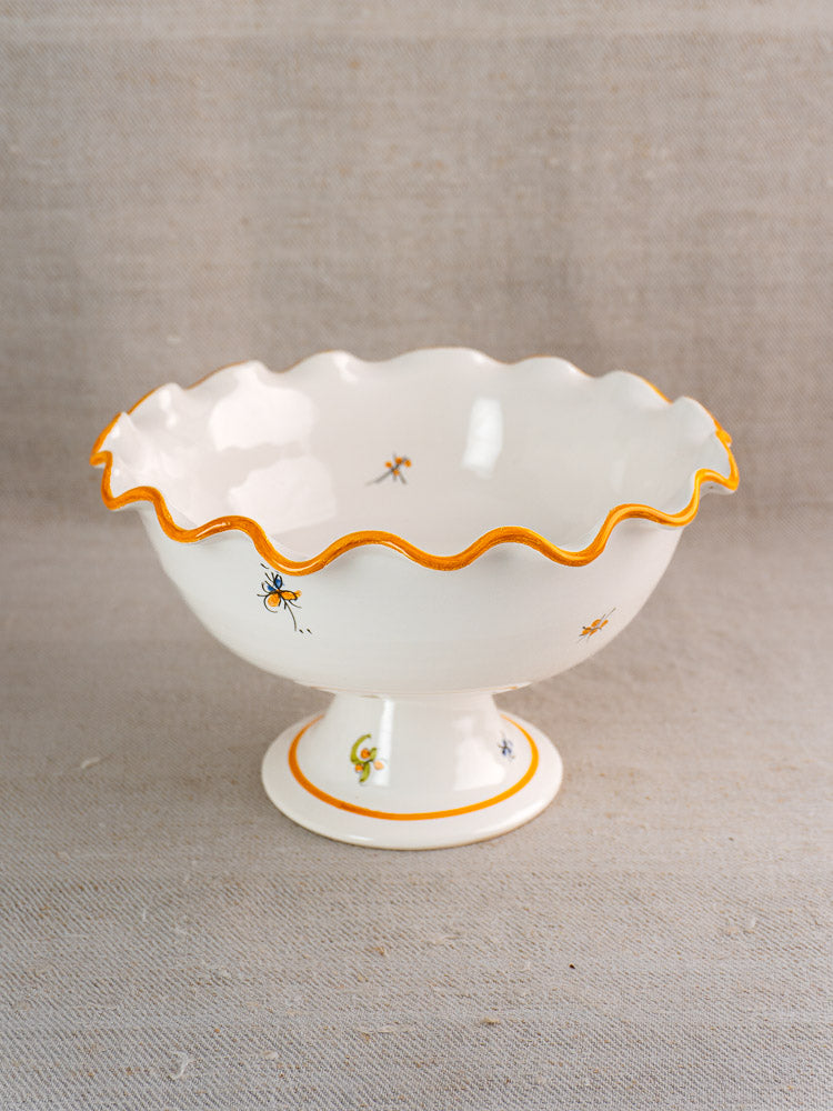Pair of vintage French Moustiers-style faience compotes with orange wavy rims and insect motifs on fabric.