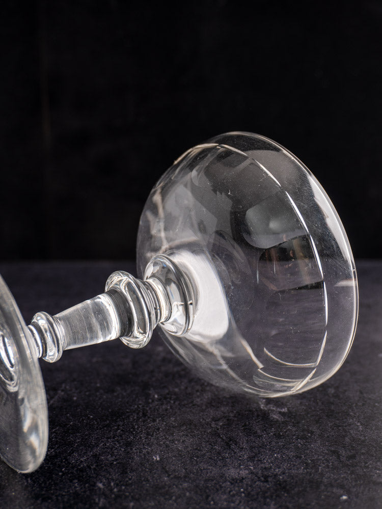 Antique French hand-blown Champagne coupe, late 19th century, on its side with reflections on stem and bowl.