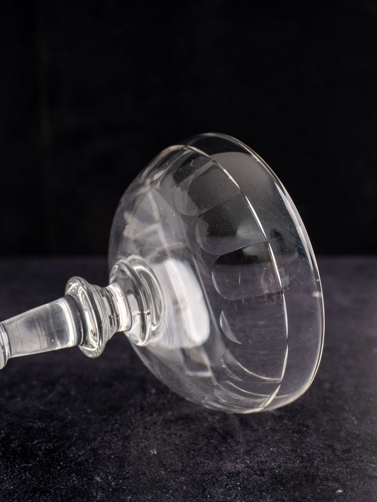 Pair of late 19th-century French hand-blown champagne coupes with rounded bowls on a dark background.