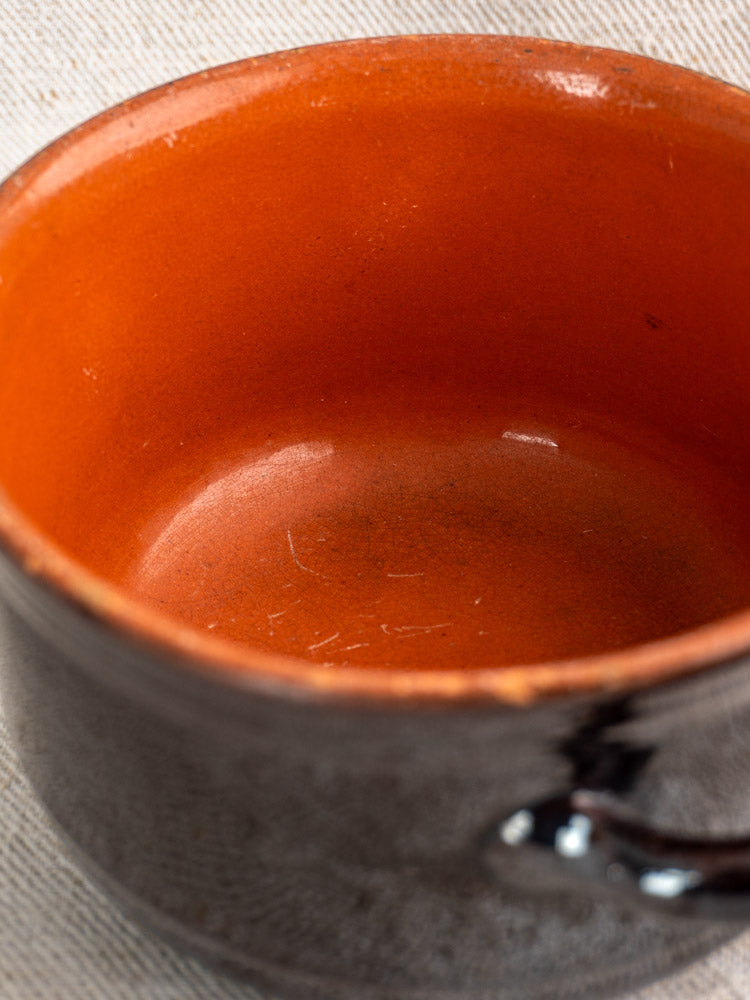 Vintage Albisola glazed earthenware Italian cooking pot by Coop. Stov., glossy orange interior, on light fabric surface.