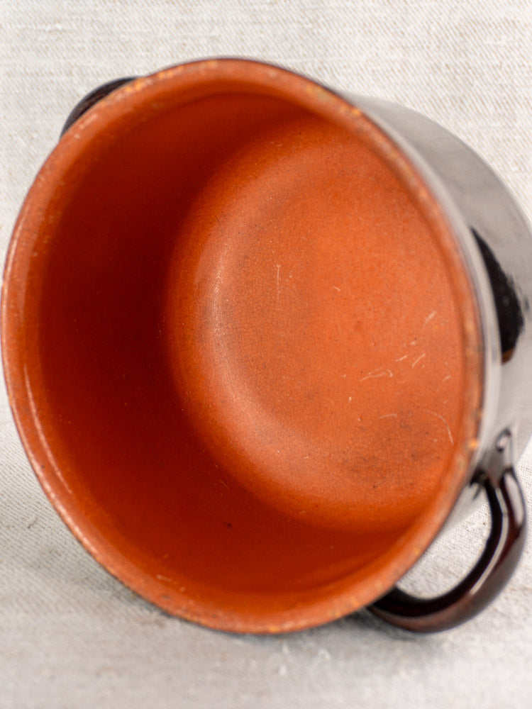 Vintage Italian Albisola glazed earthenware cooking pot with reddish-brown interior and two handles on light textured surface.