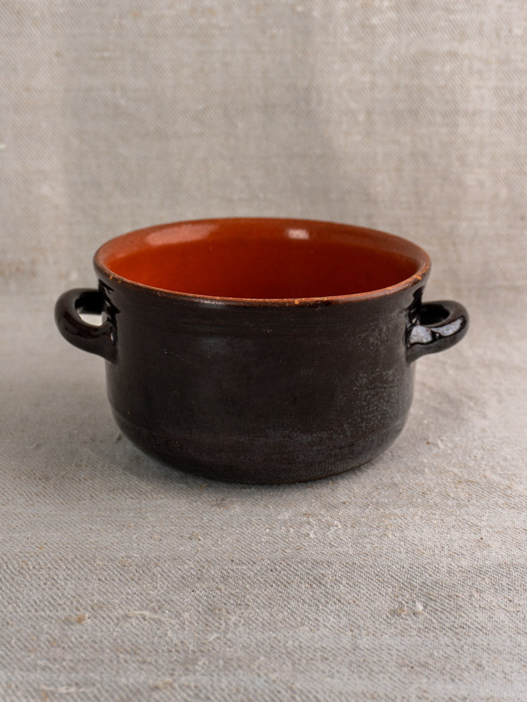 Albisola vintage Italian dark brown glazed earthenware pot with orange interior on beige textured fabric surface.