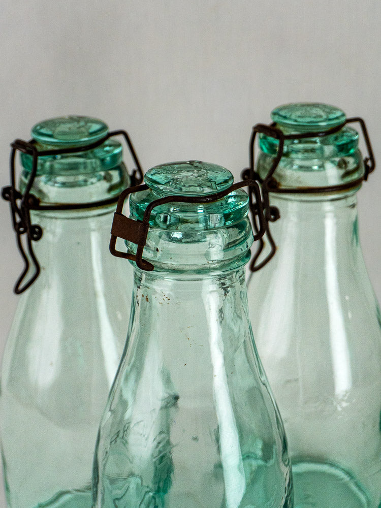 Three antique French La Lorraine preserving bottles in aqua glass with metal clasps and stoppers.
