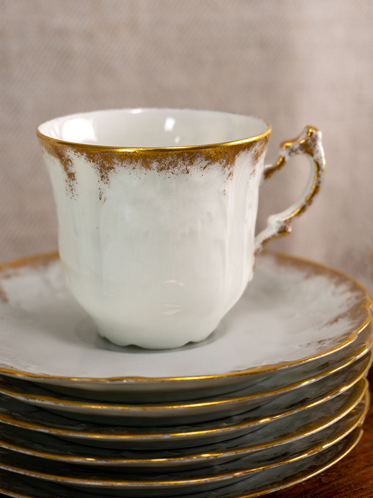 Antique French Limoges demitasse teacup by Lafarge & Cie with gold trim, stacked on matching plates.