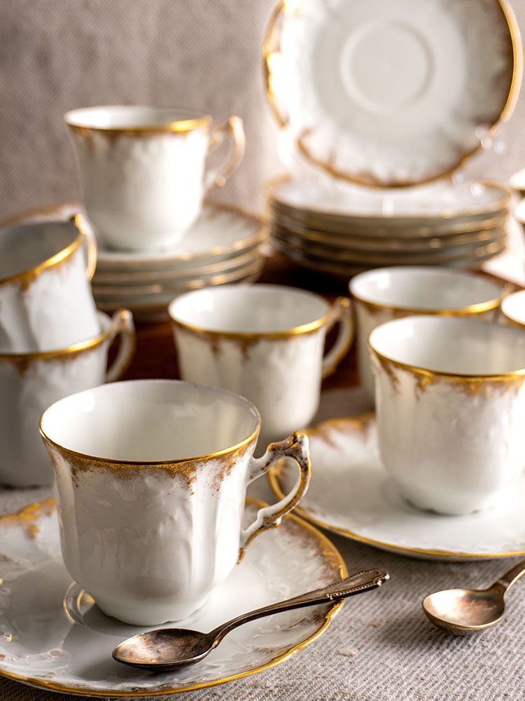French porcelain coffee cups with gold rims, matching saucers, and Lafarge & Cie Limoges plates.