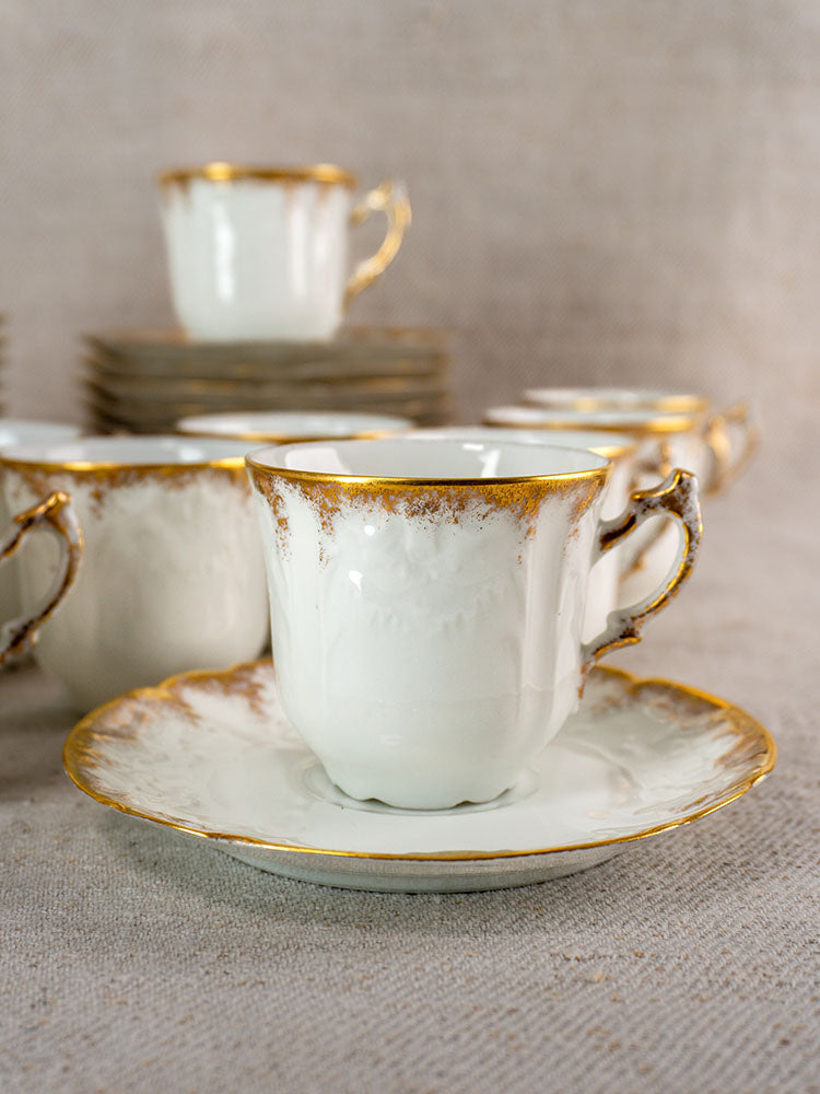 White Limoges teacup with gold trim on saucer, Lafarge & Cie Demitasse Service, soft background.
