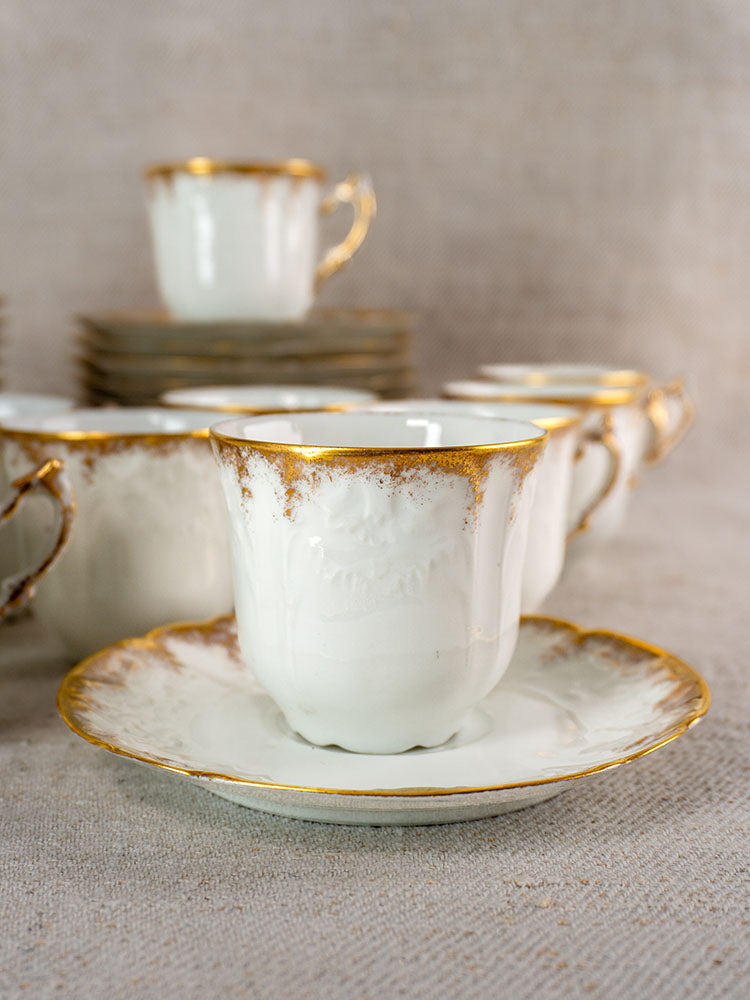 Antique French Limoges demitasse service for 12 with gold-trimmed white porcelain cups and saucers.