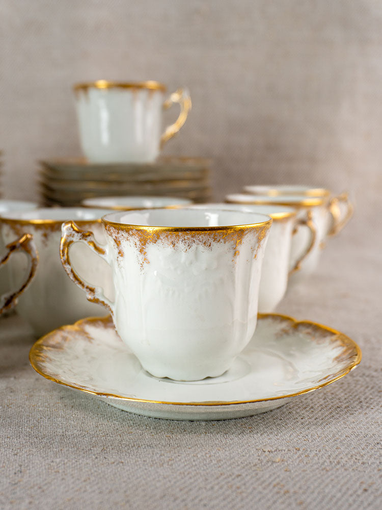 French Limoges antique demitasse cup and saucer with gold trim, white porcelain; matching set on fabric.