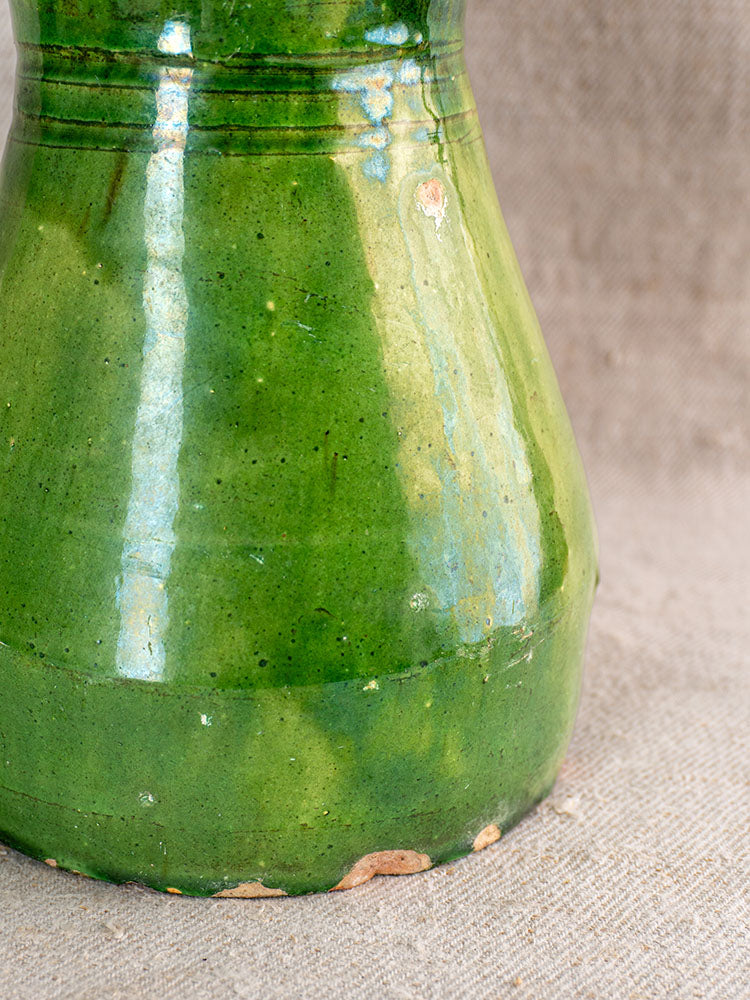 19th century French terracotta vase with emerald green glaze, scalloped rim, and ridged detail on beige fabric background.