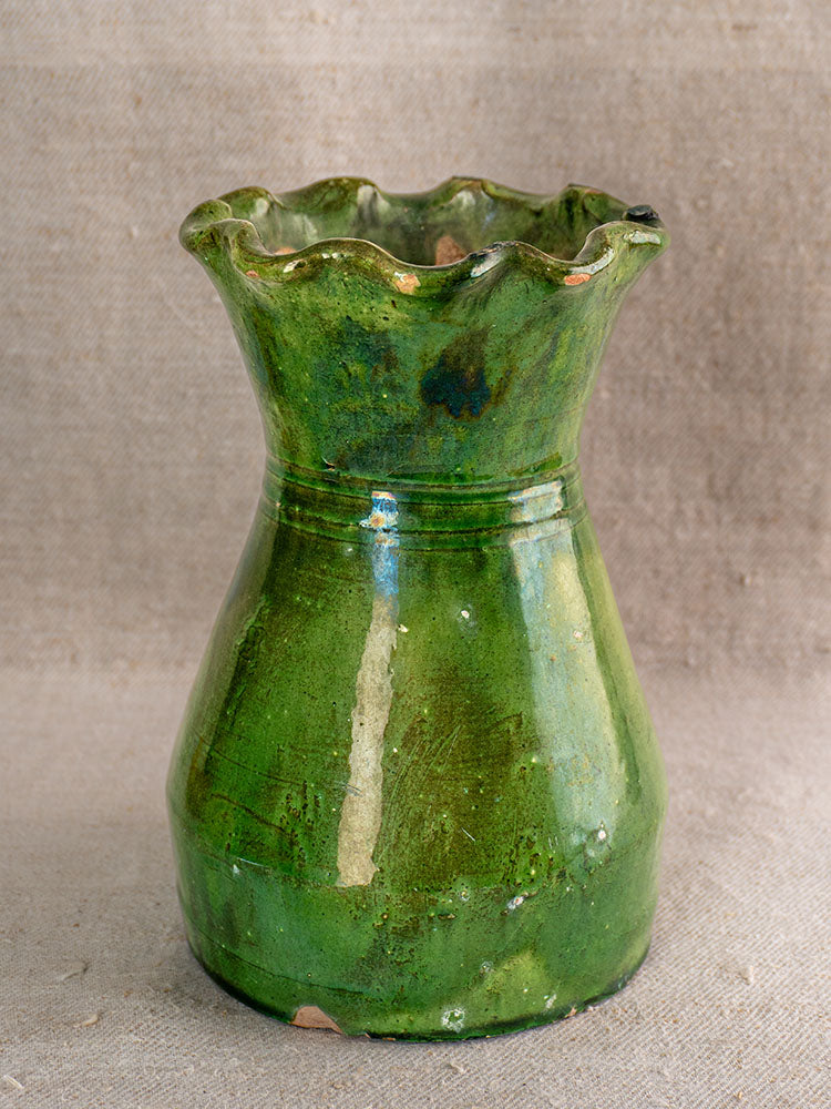 19th century French green glazed terracotta vase with scalloped rim and glossy finish on neutral fabric background.