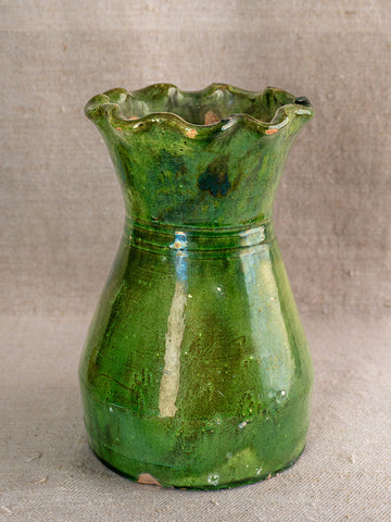 19th century French green glazed terracotta vase with scalloped rim and glossy finish on neutral fabric background.