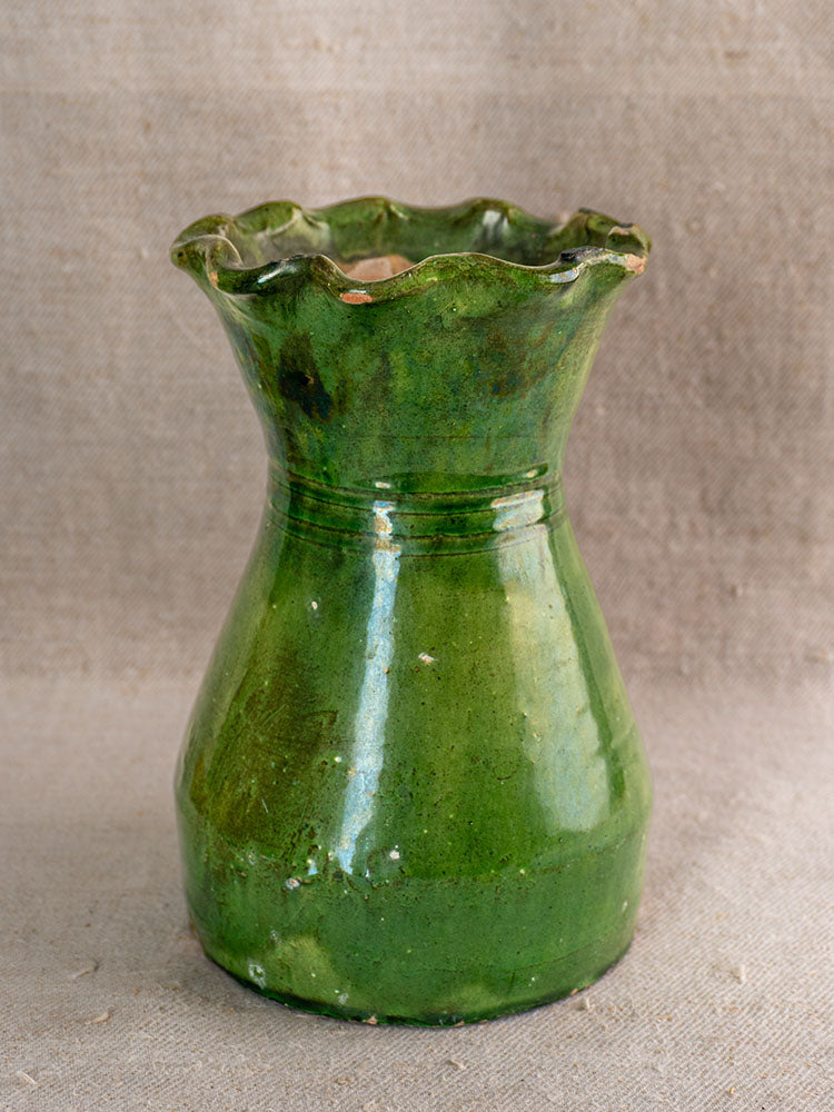 19th century French green glazed terracotta vase with scalloped rim on neutral textured fabric background.