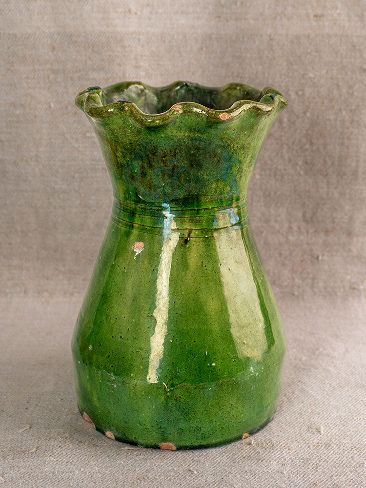 19th century French green glazed terracotta vase with scalloped rim, glossy finish, minor chips on textured neutral fabric background.