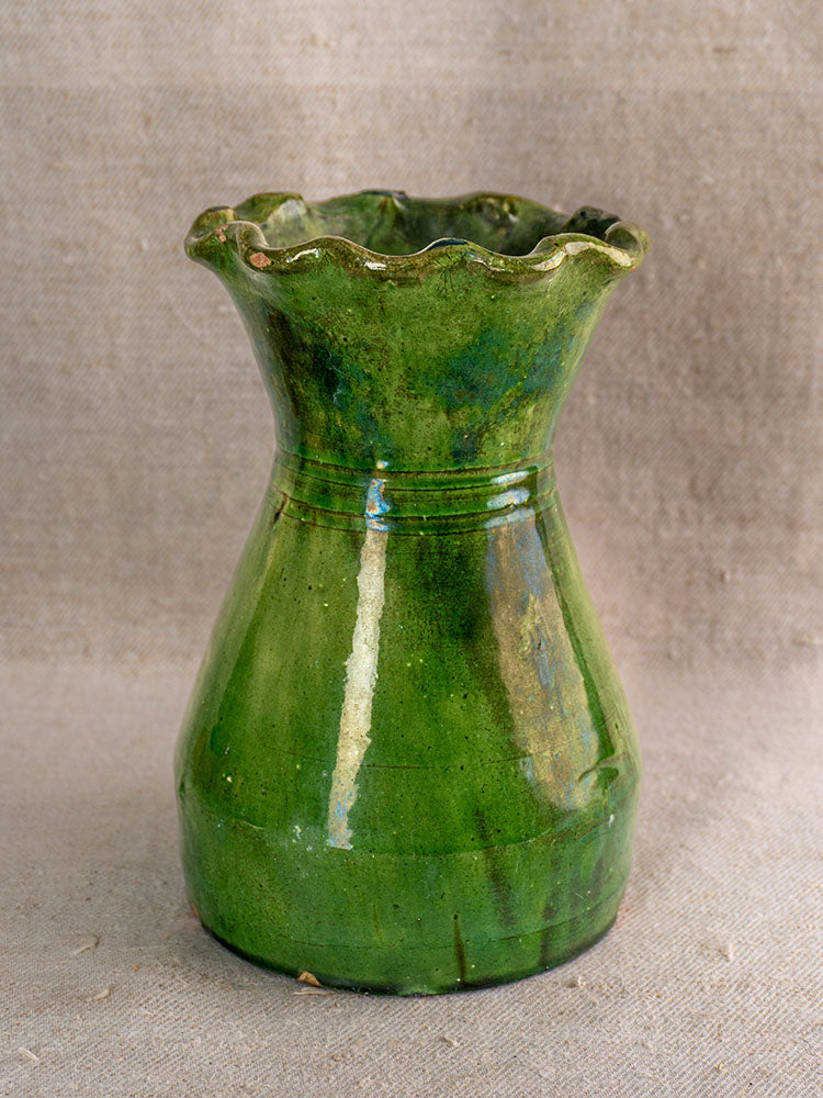 19th century French green glazed terracotta vase with scalloped rim on beige textured fabric background.