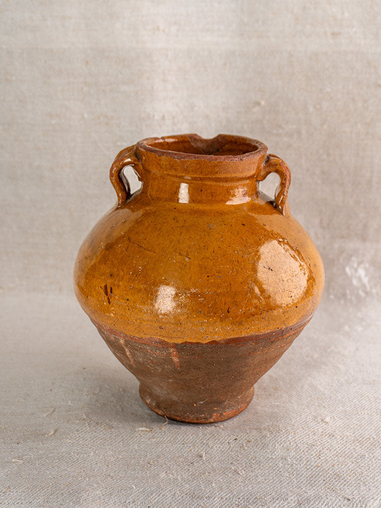 Antique French glazed earthenware olive oil jar, late 19th century, glossy brown top, matte lower half on textured fabric.