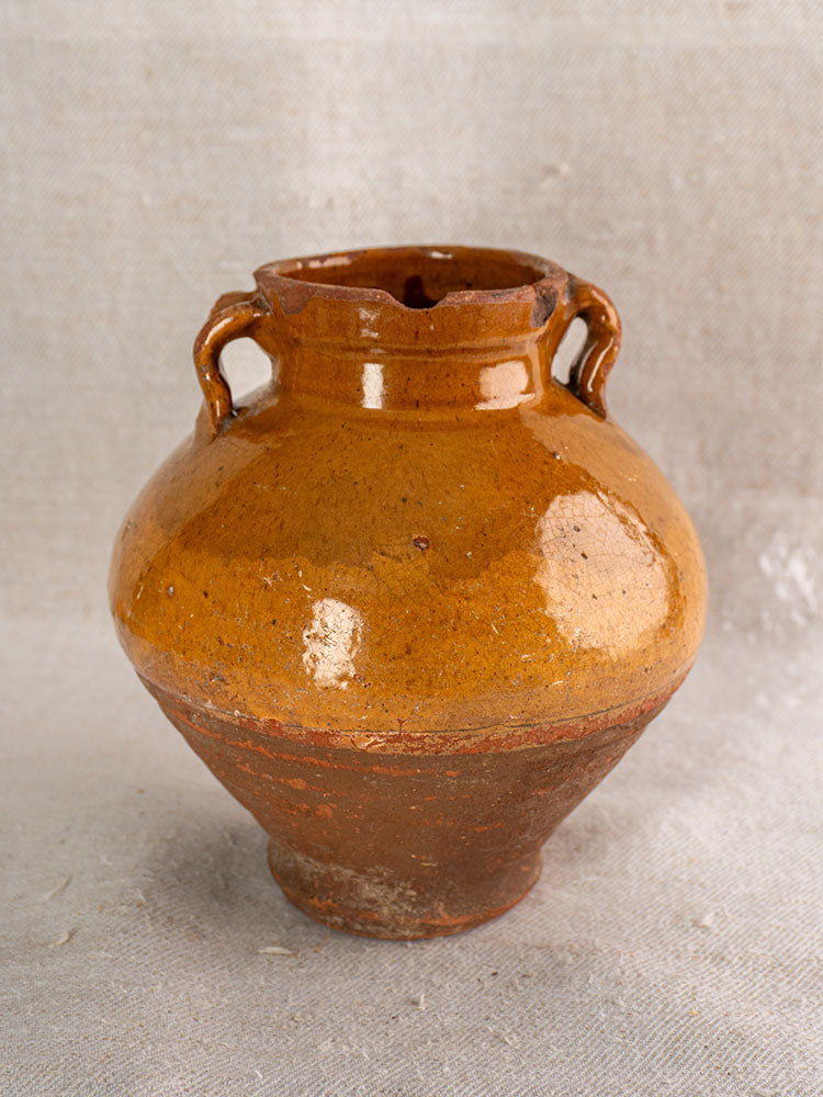 Antique French olive oil jar, late 19th century glazed earthenware, rustic brown, with neck handles on beige fabric.