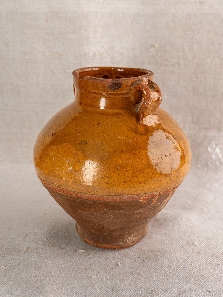 Late 19th c. French olive oil jar in glazed earthenware, round body, brown top, unglazed base, neutral background.
