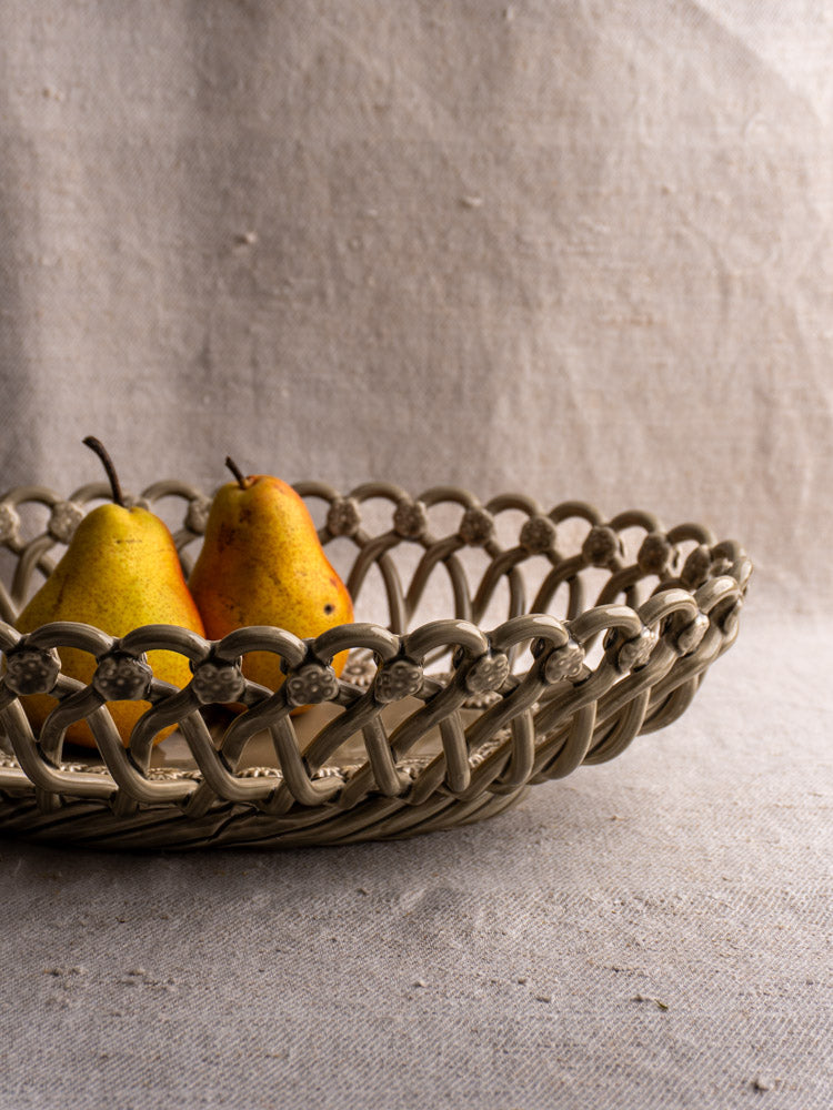Large vintage Pichon Uzès oval ceramic basket in Provence faience with two yellow pears on beige textured fabric.