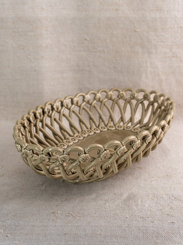 Large vintage Pichon Uzès ceramic basket with lattice and floral details on beige textured fabric.