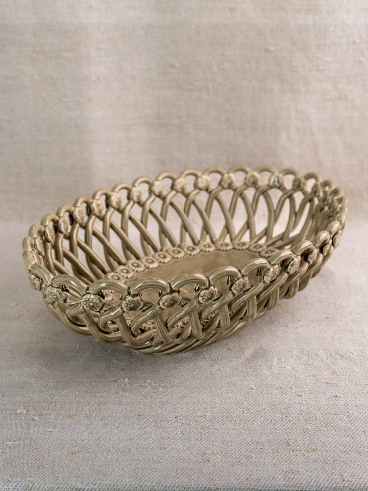 Large vintage Pichon Uzès ceramic basket with intricate oval latticework on a textured beige fabric surface.