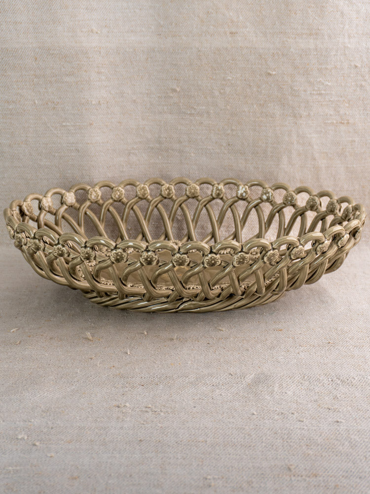 Large vintage Pichon Uzès oval ceramic basket with circular lattice design on light beige textured fabric background.