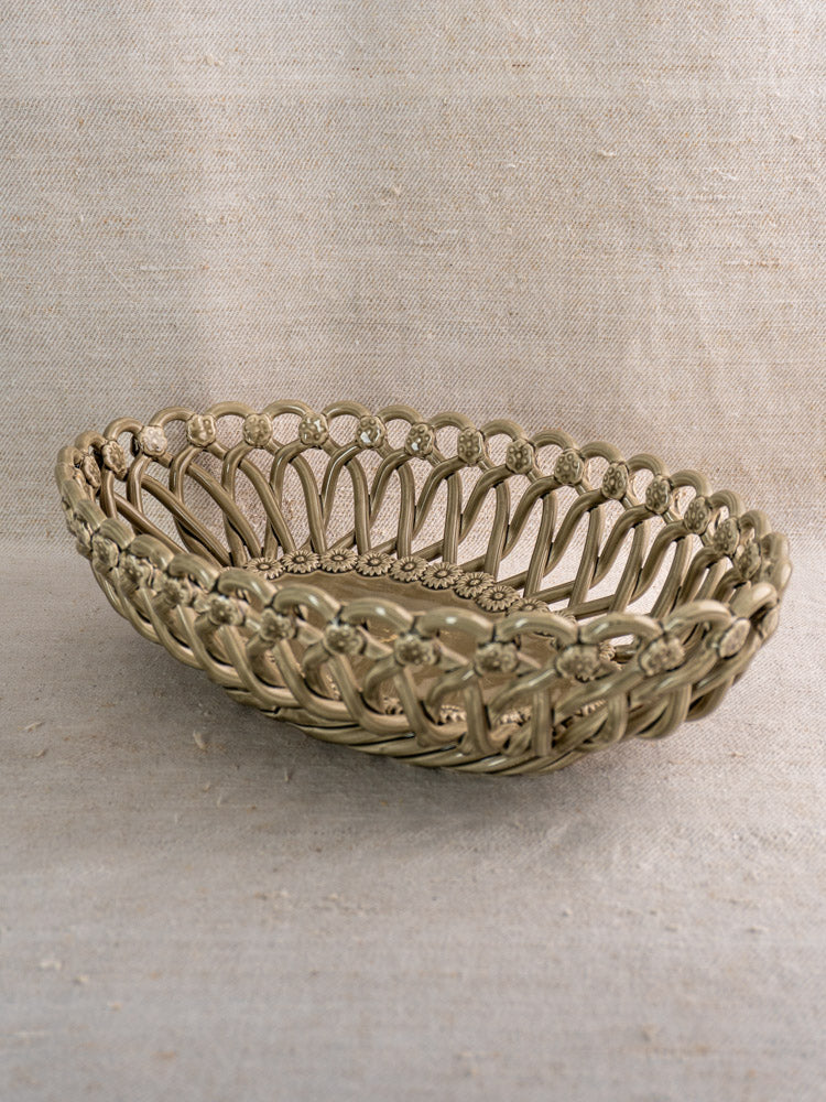 Large vintage Pichon Uzès ceramic basket with intricate pattern on textured beige fabric surface and matching background.