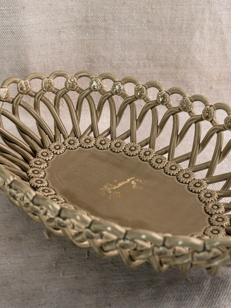 Large vintage Pichon Uzès Provence faience basket with open-weave and floral rim, on beige textured fabric.