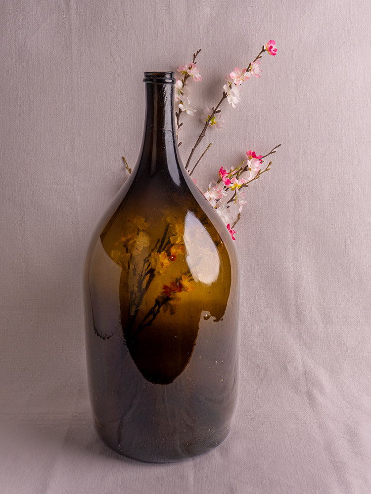 Antique French hand blown olive green glass wine bottle, 19th century, plain white background.