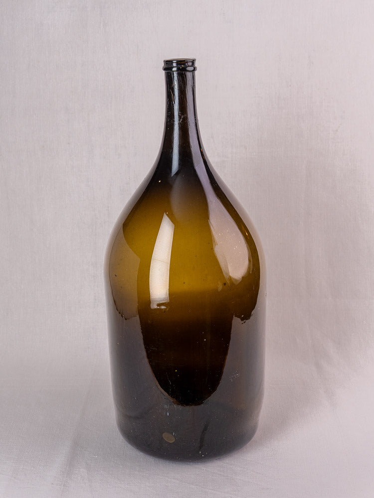 Antique French hand blown olive green glass wine bottle, 19th century, plain white background.