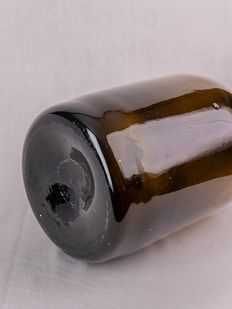 Antique French hand-blown olive green wine bottle, 19th century, resting on light fabric.