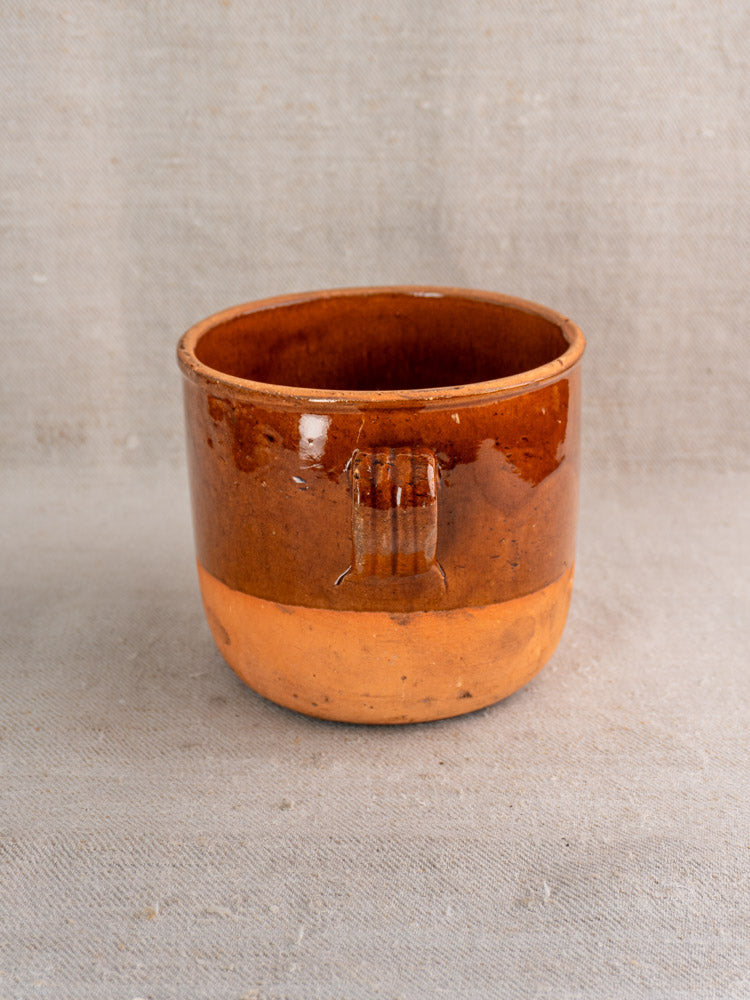 Antique French Digoin confit pot, mid 20th century glazed earthenware, ridged handle, on neutral fabric background.