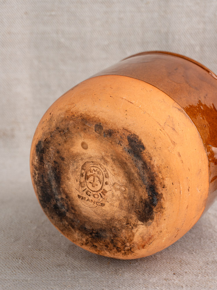 Antique French Digoin confit pot with stamped maker’s mark and gentle wear on neutral fabric background.