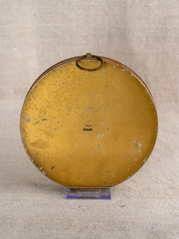 Scratched round gold metal tin labeled “Vintage French Lincoln Thermometer | Gilt Wall Dial” on plastic stand.