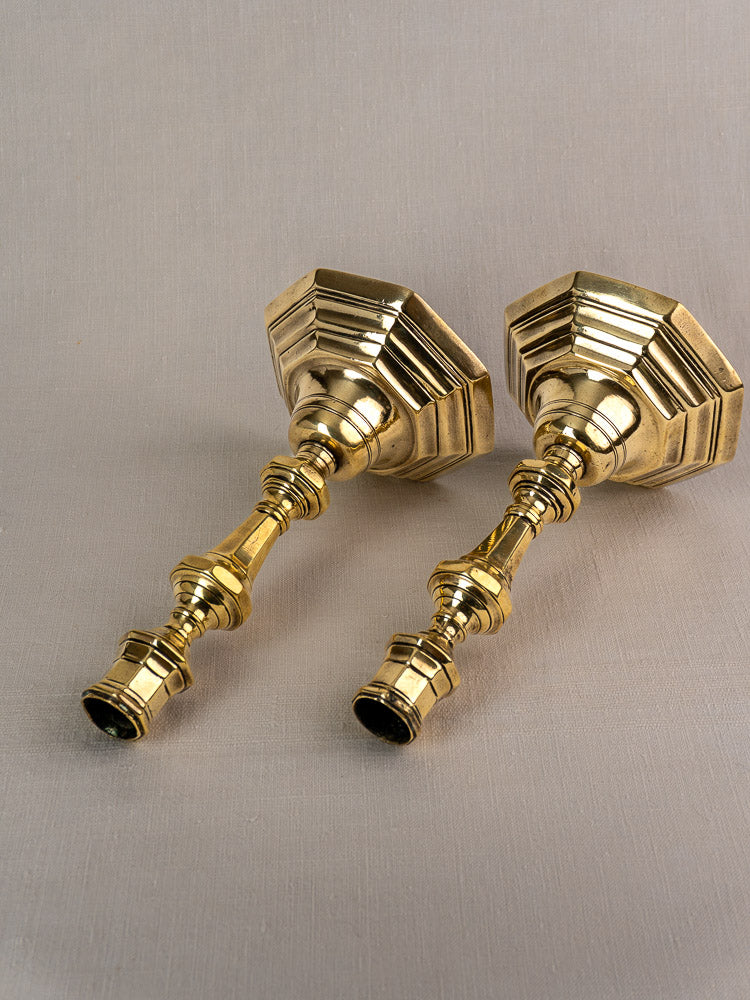 Antique French brass candlesticks, Régence period, displayed on light beige fabric for elegant presentation.