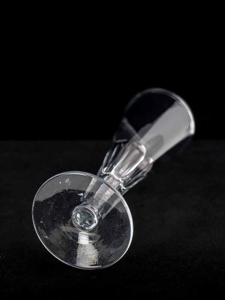 Antique French cut crystal champagne flute, early 19th century, shown resting on its side against a black background.