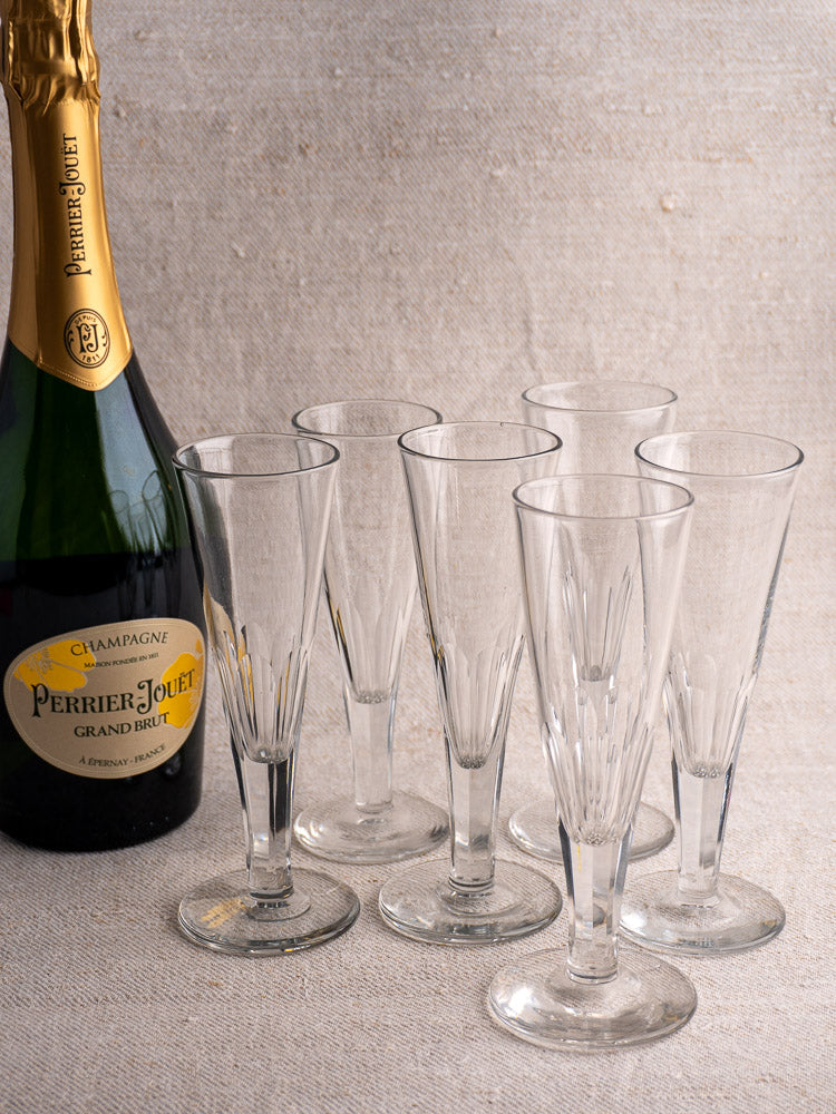 Early 19th-century antique French cut crystal champagne flutes with Perrier-Jouët Grand Brut on a light beige surface.